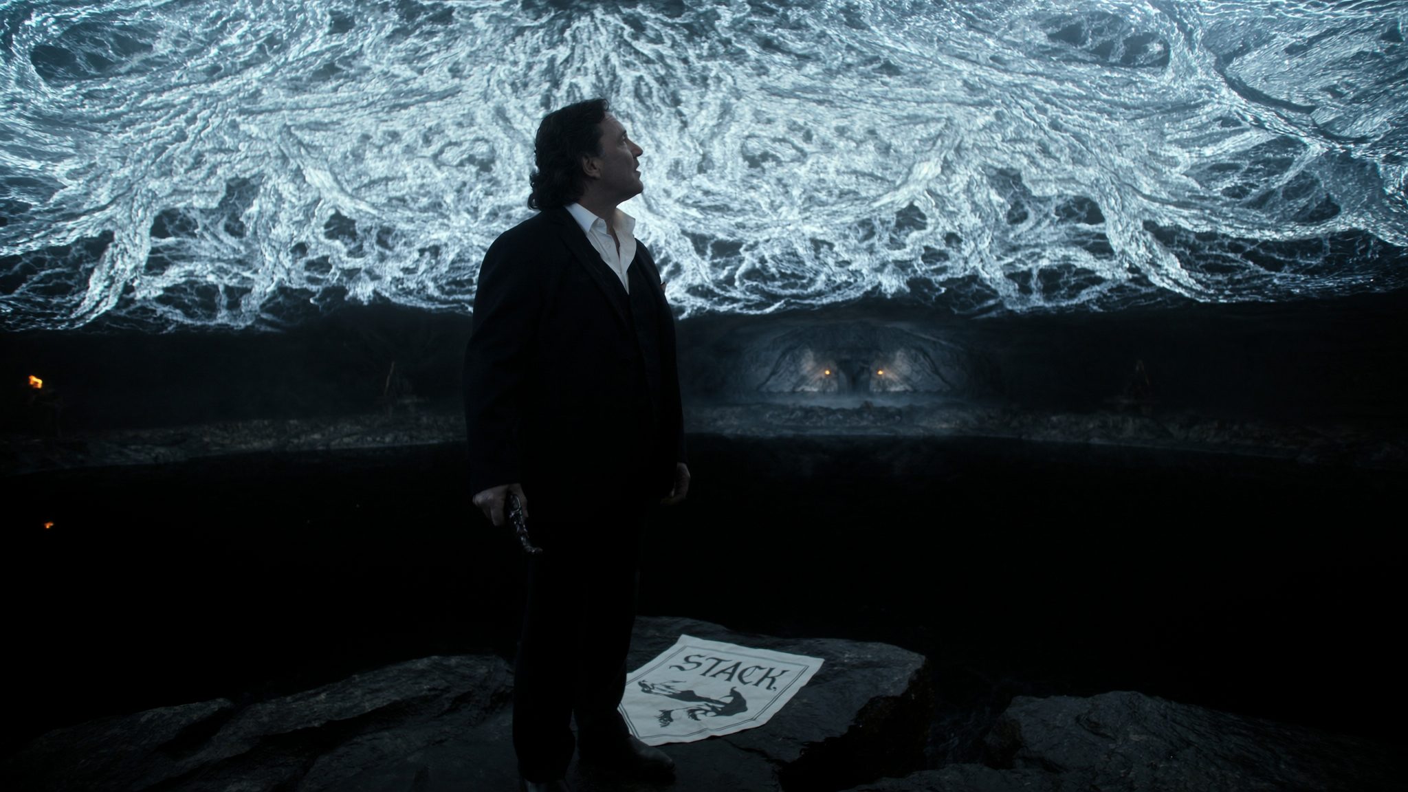 Operator in the Hollow Hill underground beneath the great weirwood, looking up at a canopy of glowing pale-blue luminescent roots. Heraldic banner reads STACK.