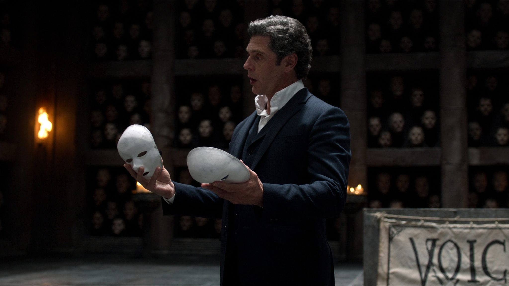 Operator in the Hall of Faces at Braavos, holding two plain porcelain masks. Heraldic banner reads VOICE.